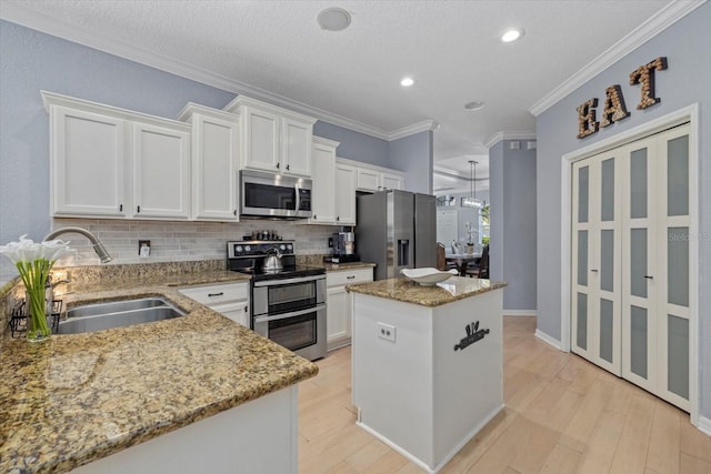 259 Golden Harbour Trl, Bradenton, FL 34212 - kitchen with light wood finished floors, a center island, appliances with stainless steel finishes, white cabinetry, and a sink