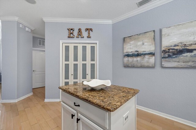 259 Golden Harbour Trl, Bradenton, FL 34212 - kitchen featuring dark stone counters, light wood finished floors, crown molding, and white cabinetry