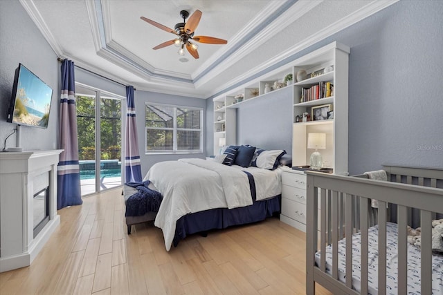 259 Golden Harbour Trl, Bradenton, FL 34212 - bedroom featuring a tray ceiling, a textured wall, light wood-type flooring, and ornamental molding