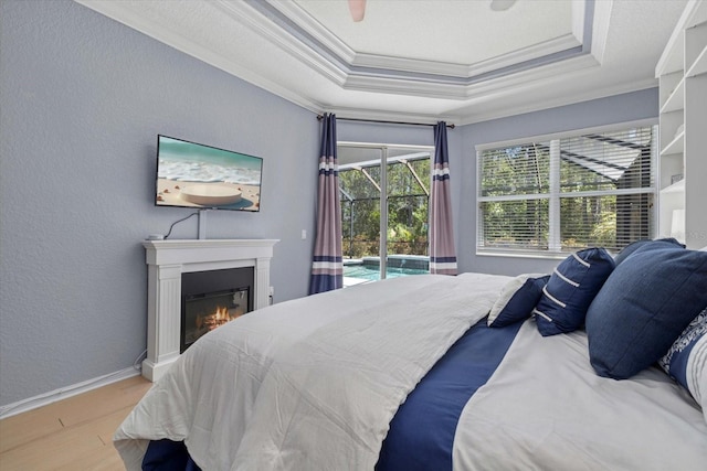 259 Golden Harbour Trl, Bradenton, FL 34212 - bedroom featuring access to outside, a tray ceiling, a glass covered fireplace, wood finished floors, and crown molding