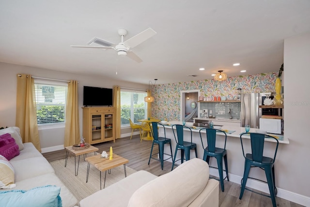 living room featuring wallpapered walls, plenty of natural light, baseboards, and light wood-style floors