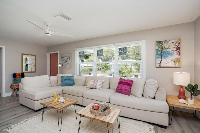 living room featuring light wood-type flooring, a ceiling fan, baseboards, and visible vents