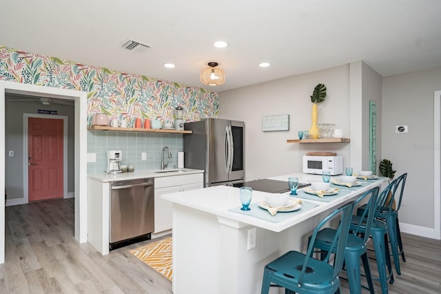 kitchen with open shelves, light countertops, a sink, and stainless steel appliances