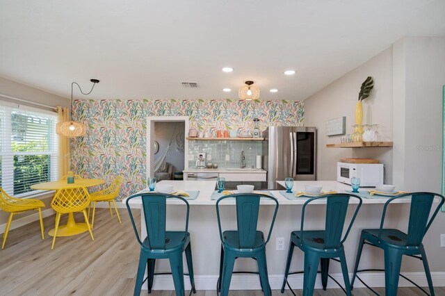 kitchen with light countertops, a sink, visible vents, smart refrigerator, and white microwave
