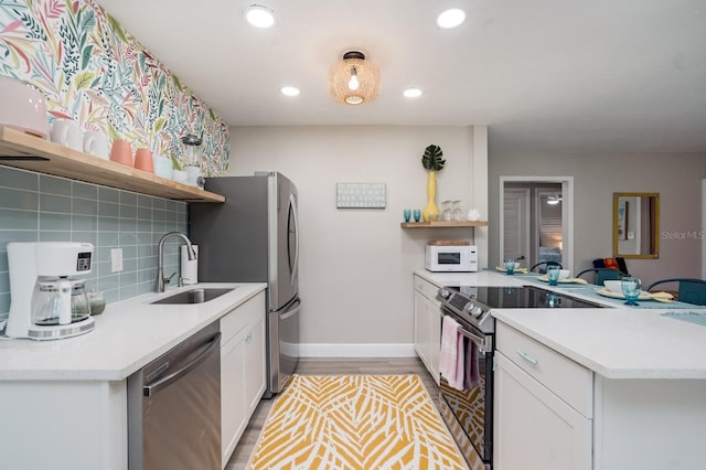 kitchen with a sink, stainless steel appliances, open shelves, and a peninsula