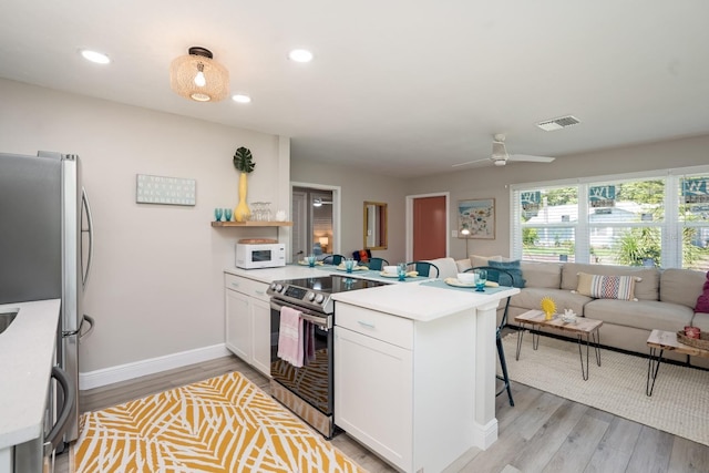 kitchen with open floor plan, light countertops, a peninsula, and appliances with stainless steel finishes