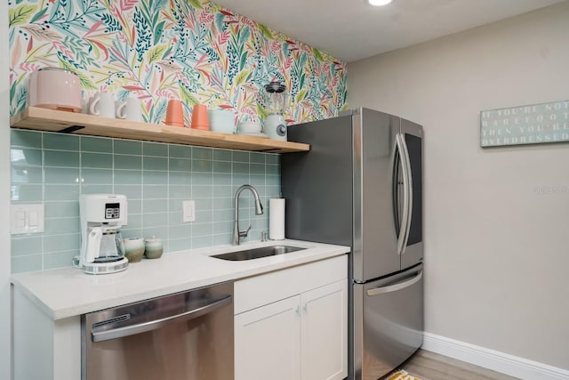 kitchen with light countertops, backsplash, open shelves, a sink, and stainless steel appliances