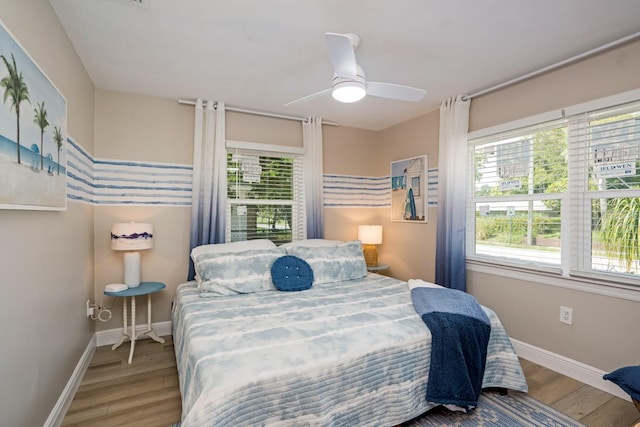 bedroom featuring baseboards, wood finished floors, and ceiling fan