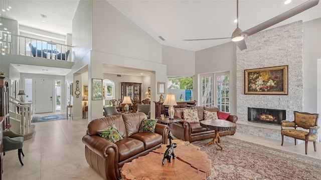 living room with a high ceiling, ceiling fan, and a fireplace