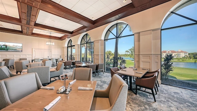 dining space featuring beam ceiling, wainscoting, a high ceiling, a decorative wall, and coffered ceiling