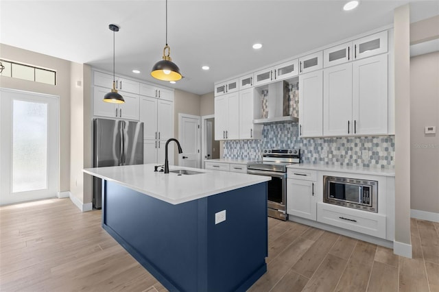 kitchen with light countertops, a sink, backsplash, appliances with stainless steel finishes, and wall chimney range hood