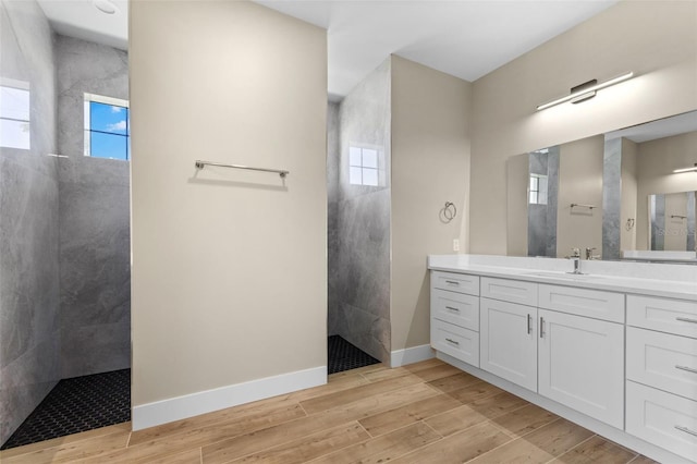 full bathroom featuring baseboards, wood finished floors, a walk in shower, and vanity