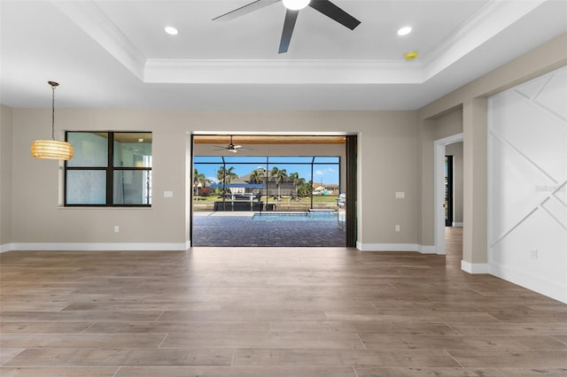 spare room with a tray ceiling, wood finished floors, and a ceiling fan