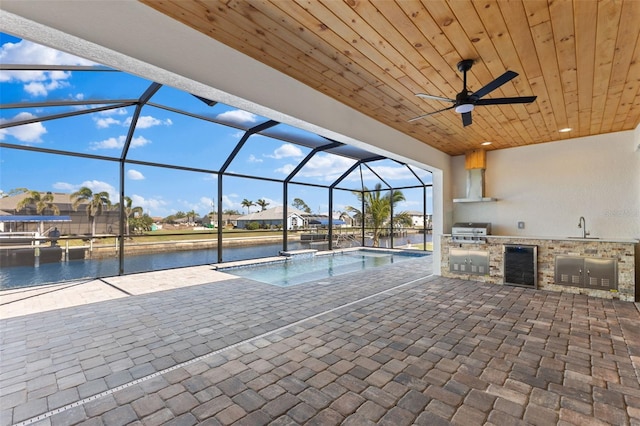pool with exterior kitchen, area for grilling, a patio, glass enclosure, and a sink