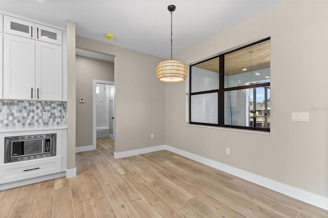 unfurnished dining area with baseboards and light wood finished floors