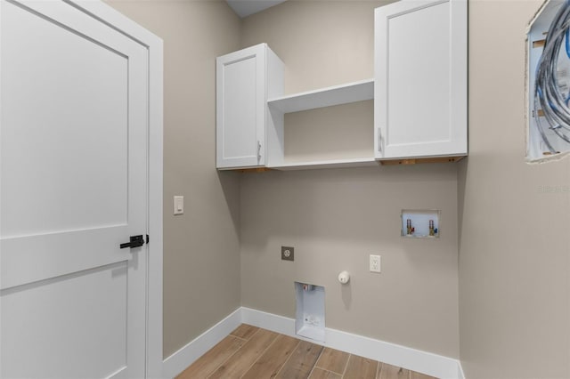 clothes washing area featuring hookup for an electric dryer, baseboards, light wood-style flooring, cabinet space, and washer hookup