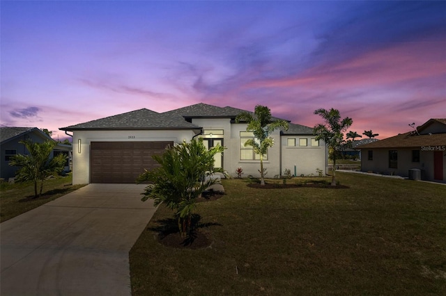 view of front of property with driveway, central air condition unit, stucco siding, an attached garage, and a lawn