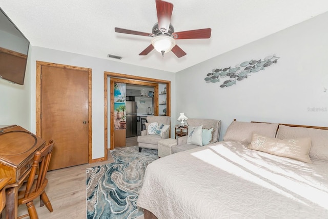 2070 59th St, Sarasota, FL 34243 - bedroom with freestanding refrigerator, light wood finished floors, and a ceiling fan