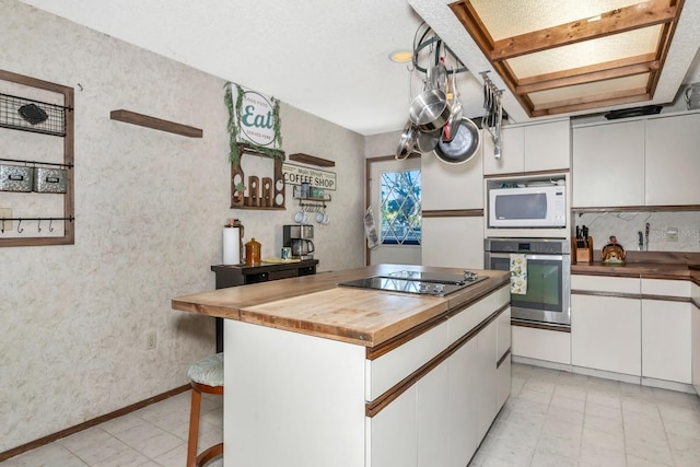 2070 59th St, Sarasota, FL 34243 - kitchen with stainless steel oven, black electric stovetop, white microwave, butcher block countertops, and white cabinets