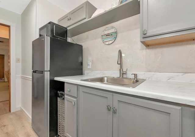 2070 59th St, Sarasota, FL 34243 - kitchen with gray cabinetry, freestanding refrigerator, light countertops, black microwave, and a wainscoted wall