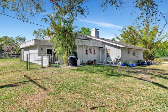 2070 59th St, Sarasota, FL 34243 - back of property with a gate, a chimney, and board and batten siding