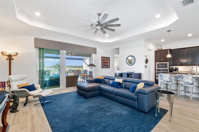25325 Longmeadow Dr, Punta Gorda, FL 33955 - living room with visible vents, a tray ceiling, ornamental molding, ceiling fan, and light wood-style floors