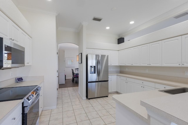 4606 Lake Fox Pl, Parrish, FL 34219 - kitchen with stainless steel appliances, arched walkways, ornamental molding, light tile patterned floors, and light countertops