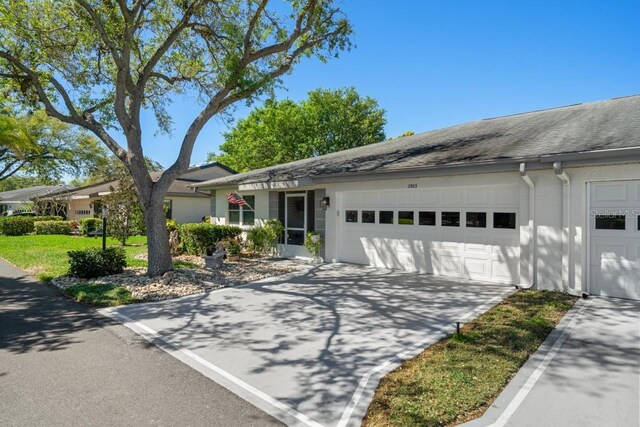 ranch-style house featuring stucco siding, driveway, and an attached garage