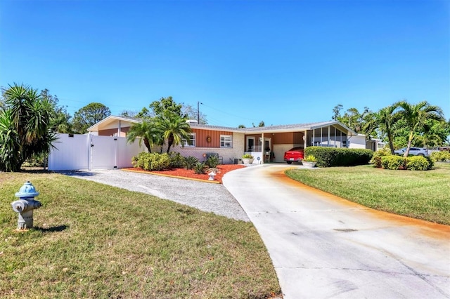 ranch-style home with a gate, fence, a front yard, driveway, and a carport