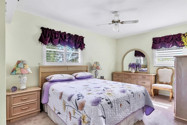 bedroom with multiple windows, a ceiling fan, and light carpet