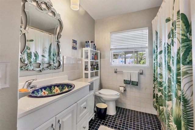 full bathroom featuring tile patterned floors, toilet, vanity, wainscoting, and tile walls