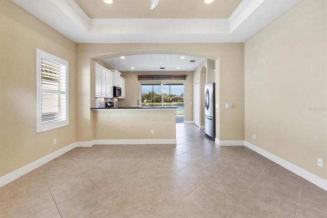 unfurnished room featuring arched walkways, ornamental molding, and a raised ceiling
