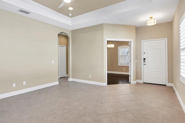 unfurnished room with a ceiling fan, visible vents, arched walkways, light tile patterned floors, and baseboards