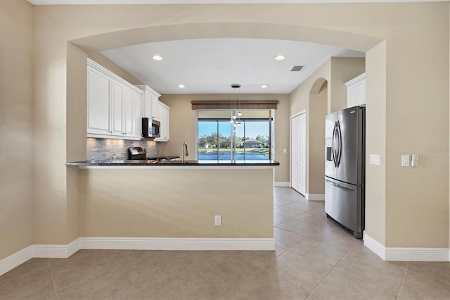 kitchen with dark countertops, appliances with stainless steel finishes, a peninsula, white cabinetry, and visible vents