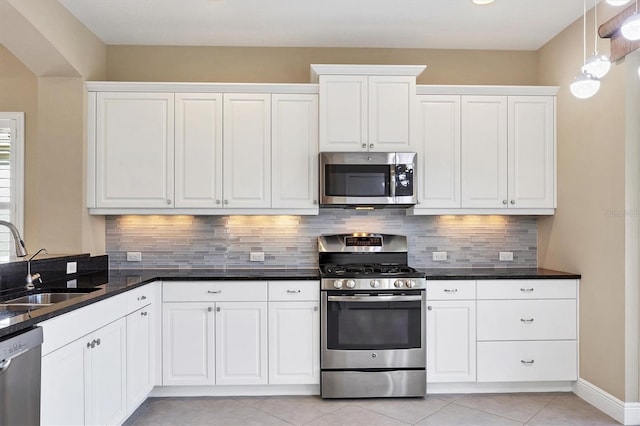 kitchen with a sink, appliances with stainless steel finishes, white cabinets, and light tile patterned floors