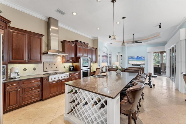 kitchen with visible vents, a sink, wall chimney range hood, gas stovetop, and stainless steel double oven