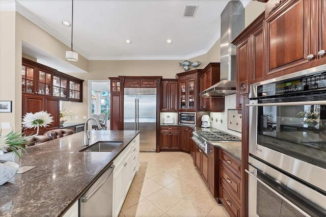 kitchen featuring wall chimney range hood, crown molding, appliances with stainless steel finishes, pendant lighting, and a sink