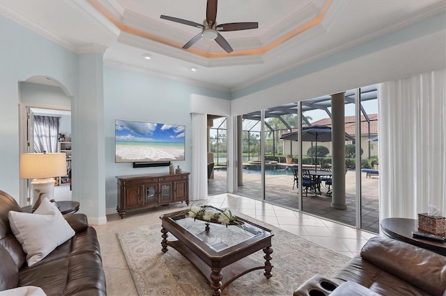 living area with a wealth of natural light, light tile patterned floors, a ceiling fan, and a raised ceiling