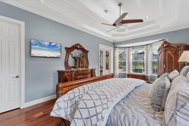 bedroom featuring ceiling fan, dark wood finished floors, a tray ceiling, ornamental molding, and baseboards