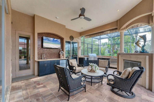 view of patio featuring a grill, an outdoor kitchen, a ceiling fan, and glass enclosure