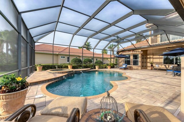 view of pool featuring a patio, a pool with connected hot tub, and glass enclosure