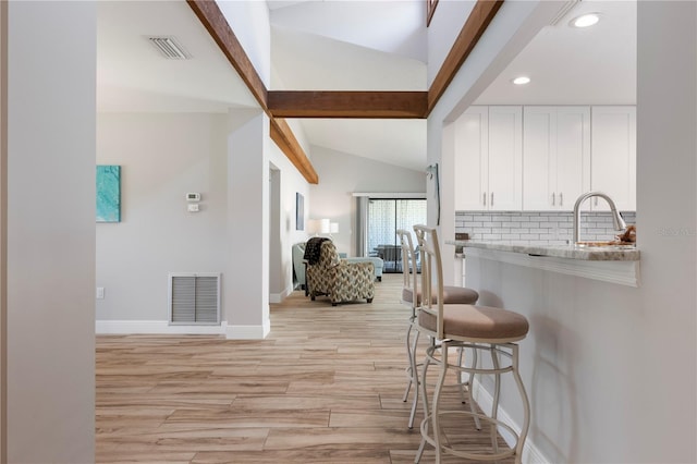 3804 Sun Eagle Ln, Bradenton, FL 34210 - kitchen featuring visible vents, tasteful backsplash, white cabinetry, and lofted ceiling with beams