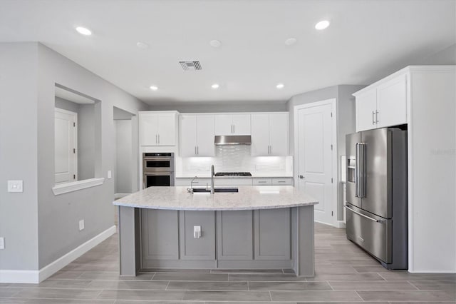 11717 Blue Hill Trl, Lakewood Ranch, FL 34211 - kitchen with visible vents, a sink, decorative backsplash, under cabinet range hood, and appliances with stainless steel finishes