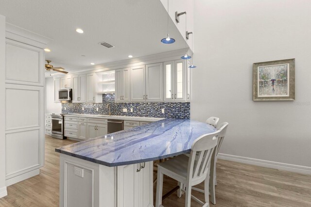 1928 Harbourside Dr Unit 1403, Longboat Key, FL 34228 - kitchen with appliances with stainless steel finishes, light wood-type flooring, tasteful backsplash, a kitchen breakfast bar, and baseboards