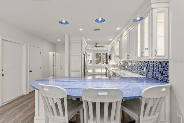 1928 Harbourside Dr Unit 1403, Longboat Key, FL 34228 - kitchen featuring a sink, light wood finished floors, white cabinets, a peninsula, and tasteful backsplash