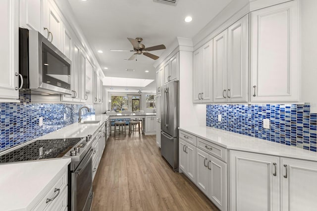 1928 Harbourside Dr Unit 1403, Longboat Key, FL 34228 - kitchen with appliances with stainless steel finishes, a sink, ceiling fan, light wood finished floors, and backsplash