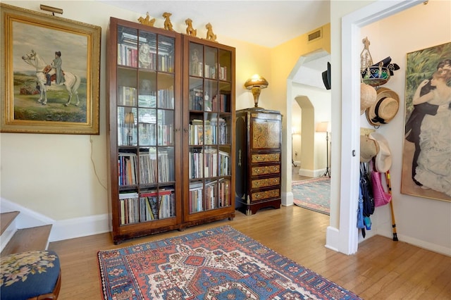 sitting room featuring visible vents, wood finished floors, arched walkways, baseboards, and stairs