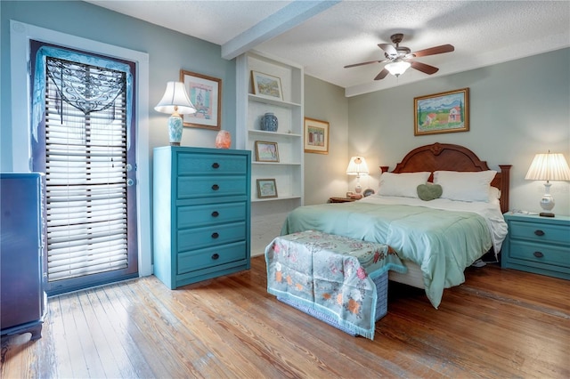 bedroom featuring access to outside, a ceiling fan, wood-type flooring, and a textured ceiling