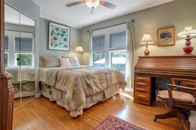 bedroom with a ceiling fan, light wood-style floors, and a textured ceiling