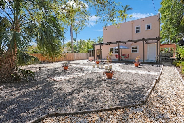 rear view of house featuring stucco siding, a patio area, a fenced backyard, and a pergola